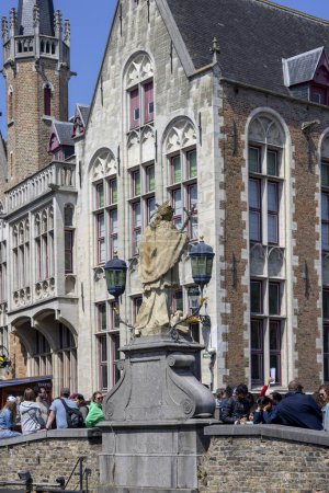 Foto de Brujas, Bélgica - 19 de mayo de 2023: Estatua de Juan de Nepomuk sobre la piedra Puente de Nepomuceno (Nepomucenusbrug) sobre el agua Canal Dijver - Imagen libre de derechos