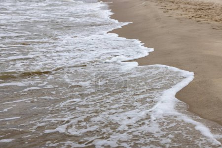 Vue pittoresque sur la plage de sable de la mer Baltique, eau mousseuse coulant dans le sable, Miedzyzdroje, Pologne