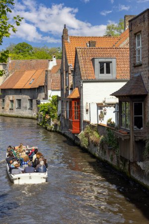 Foto de Brujas, Bélgica - 19 de mayo de 2023: Vista desde Mariabrug (Puente de María) de Rosary Quay (Rozenhoedkaai) y los turistas en un barco en el canal de agua Dijver Canal - Imagen libre de derechos