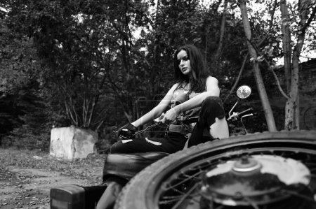 Téléchargez les photos : Photo noir-blanc d'une fille sur une moto dans la forêt - en image libre de droit