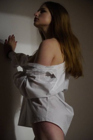 Foto de Foto de una hermosa joven con una sola camisa blanca sobre su cuerpo desnudo posando en un estudio - Imagen libre de derechos