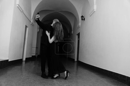 Photo for Black and white photo of a beautiful sensual woman in a black dress and a man posing for the camera - Royalty Free Image
