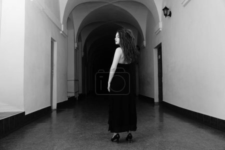 Téléchargez les photos : Photo noir et blanc d'une belle femme sensuelle dans une robe noire posant pour l'appareil photo - en image libre de droit
