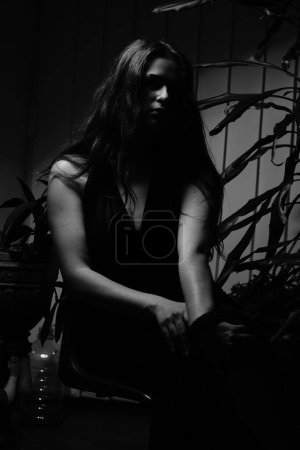 Téléchargez les photos : Photo noir et blanc d'une belle femme sensuelle dans une robe noire posant pour l'appareil photo - en image libre de droit