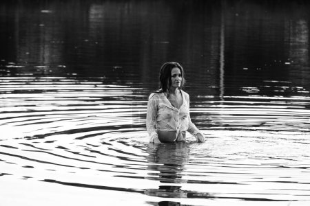 Foto de Foto en blanco y negro de una chica en un lago en el parque. pelo y ropa húmedos. - Imagen libre de derechos