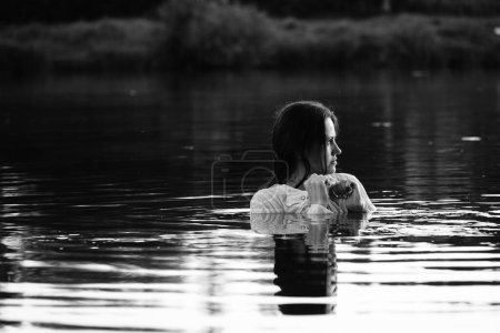 Photo for Black and white photo of a girl on a lake in the park.  wet hair and clothes. - Royalty Free Image