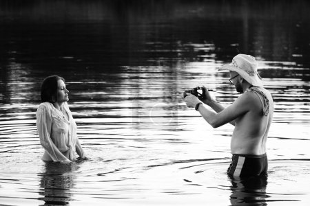 Téléchargez les photos : Photo noir et blanc du photographe prenant des photos d'une fille sur un lac dans le parc. - en image libre de droit