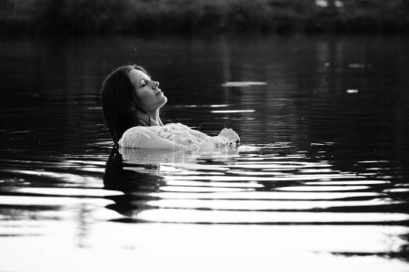 Foto de Foto en blanco y negro de una chica en un lago en el parque. pelo y ropa húmedos. - Imagen libre de derechos