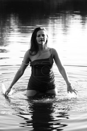 Téléchargez les photos : Photo en noir et blanc d'une fille sur un lac dans le parc. cheveux et vêtements mouillés. - en image libre de droit