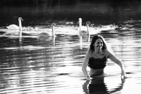 Foto de Foto en blanco y negro de una chica con cisnes en un lago en el parque. - Imagen libre de derechos