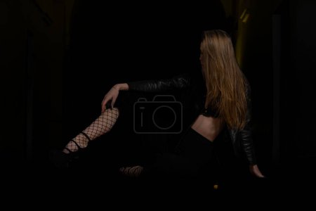 Téléchargez les photos : Femme sexy en dentelle noire lingerie et bas noirs avec des bottes noires sur noir - en image libre de droit
