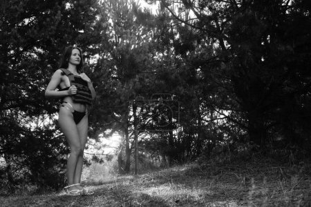 Téléchargez les photos : Photo noir-blanc d'une fille soldat à moitié nue dans la forêt - en image libre de droit