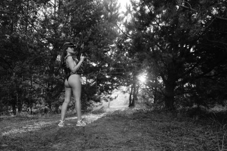 Foto de Foto en blanco y negro de una chica soldado medio desnuda en el bosque - Imagen libre de derechos