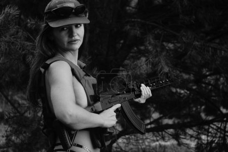 Téléchargez les photos : Photo noir-blanc d'une fille soldat à moitié nue dans la forêt - en image libre de droit