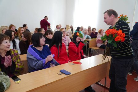 Photo for Lutsk, Ukraine: man handing out tulips to women in award student ceremony on March 8 in Volyn Professional College of the National University of Food Technologies - Royalty Free Image