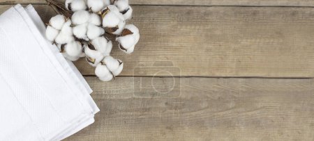 Photo for A white towel and cotton lie on a wooden background. Copy space. Banner - Royalty Free Image