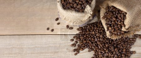 Fresh coffee beans. Coffee beans in bags on a wooden background. View from above. Copy space. Banner