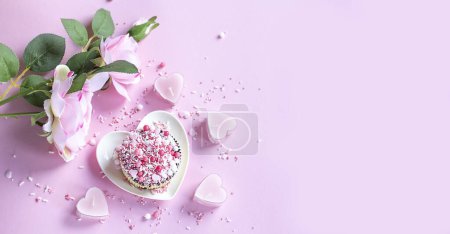 Foto de La magdalena en el plato en forma del corazón sobre el fondo rosado. Rosa rosa. Las velas rosadas - los corazones. Banner - Imagen libre de derechos