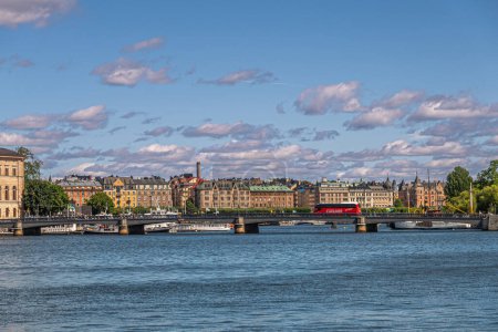 Téléchargez les photos : Suède, Stockholm - 17 juillet 2022 : Skeppholmsbron pont avec bus Cuxliner rouge à partir de Skeppsbron quay. sous nuage bleu et paysage urbain derrière. - en image libre de droit