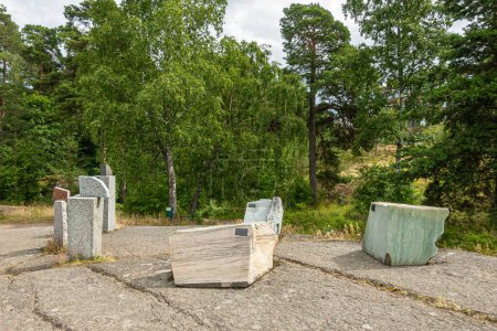 Photo for Finland, Kotka - July 18, 2022: Sopokanlahti park and lake. Brown and gray modern sculpted marble rock blocks as art on plateau under gray cloudscape. Green belt as backdrop. - Royalty Free Image