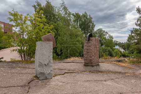 Photo for Finland, Kotka - July 18, 2022: Sopokanlahti park and lake. Brown and gray modern sculpted rock menhirs as art on plateau under gray cloudscape. Green belt as backdrop. - Royalty Free Image
