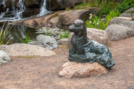 Photo for Finland, Kotka - July 18, 2022: Sopokanlahti park and lake. closeup of greenish bronze seal statue at base of waterfall - Royalty Free Image