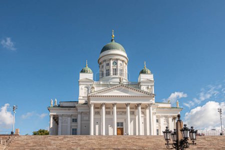 Photo for Helsinki, Finland - July 19, 2022: Lantern in front of the white Cathedral against blue sky with, featuring dome and statues. Wide brown stone staircase up front - Royalty Free Image