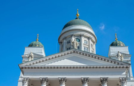 Photo for Helsinki, Finland - July 19, 2022: Pediment of white Cathedral with 3 domes with golden pinnacles against blue sky. 3 Apostle statues from left to right: Bartholomew, John, Matthew, - Royalty Free Image