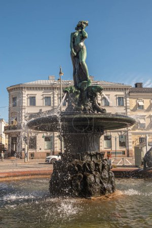 Téléchargez les photos : Helsinki, Finlande - 19 juillet 2022 : Gros plan frontal, statue de Havis Amanda dans la fontaine et place du marché à Kaartinkaupunki sous le ciel bleu. Façades grises à l'arrière - en image libre de droit