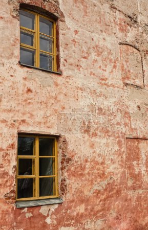 Foto de Helsinki, Finlandia - 19 de julio de 2022: Fortaleza Suomenlinna. Patrón de primer plano de astillado, anteriormente fachada de ladrillo rojo con un par de ventanas, se ha convertido en cemento beige de color con manchas rojas - Imagen libre de derechos