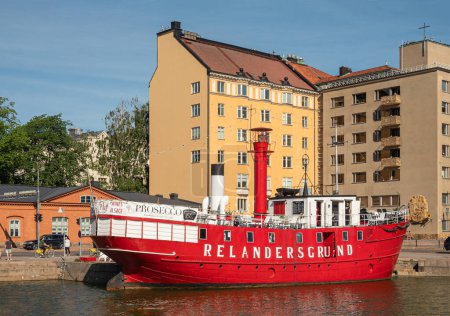 Téléchargez les photos : Helsinki, Finlande - 20 juillet 2022 : Pohjoissatama Harbor. Gros plan de bateau à vapeur vintage rouge-blanc appelé Relandersgrund Majakkalaiva, amarré au quai en face du bâtiment de façade jaune - en image libre de droit