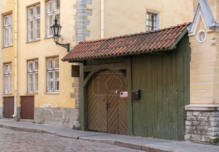 Téléchargez les photos : Estonie, Tallinn - 21 juillet 2022 : Gros plan de la porte traditionnelle en bois vert et rouge à l'arrière et parking de l'hôtel 3 Sisters dans la rue Pikk - en image libre de droit