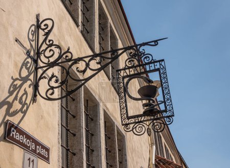Foto de Estonia, Tallin - 21 de julio de 2022: Primer plano de la pieza de metal tallado artísticamente marrón como signo de farmacia colgando en frente de la pared beige en la plaza del ayuntamiento, raekoja plats - Imagen libre de derechos