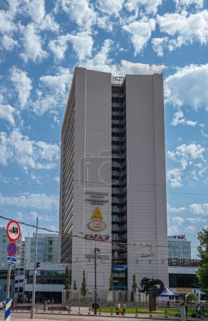 Téléchargez les photos : Estonie, Tallinn - 21 juillet 2022 : Grand bâtiment moderne abritant différentes entreprises, l'hôtel Viru et le centre de conférence sous un paysage nuageux bleu le long d'une artère animée. Statue de sirène - en image libre de droit