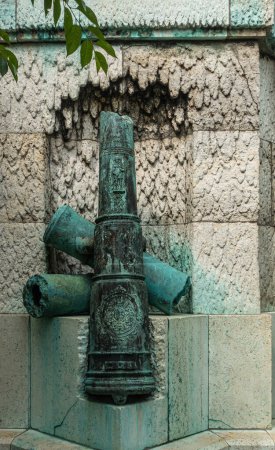 Foto de Copenhague, Dinamarca - 24 de julio de 2022: Ivar Huitfeldt Column detail. Estatua de cañones rotos verde bronce en la parte inferior de la columna de piedra marrón almirantes en Langelinie Park - Imagen libre de derechos