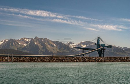 Foto de Seward, Alaska, EE.UU. - 22 de julio de 2011: Suneel materia prima y el oleoducto de carbón y grúa en el muelle en el agua verde de la Bahía de Resurrección bajo el cielo azul. Cordillera en la espalda - Imagen libre de derechos