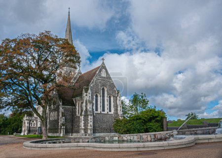Photo for Copenhagen, Denmark - September 13, 2010: Landscape. Gray and white stone Saint Albans Church under blue cloudscape with green foliage on both side and green water pond - Royalty Free Image