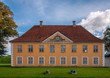 Copenhagen, Denmark - September 13, 2010: Closeup of Kastellet, citadel, yellow facade with red roof general staff building under blue cloudscape with green trees on side and lawn