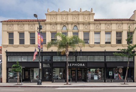Photo for Pasadena, CA, USA - June 8, 2023: Sephora shop, black facade and window on street level of historic beige facade building with mural sculptures under blue cloudscape along Colorado Blvd. - Royalty Free Image