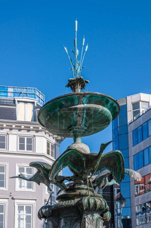 Foto de Copenhague, Dinamarca - 15 de septiembre de 2010: Primer plano de la estatua de la Fuente de la cigüeña en Amagertorv, centro de la ciudad contra el cielo azul. Arquitectura moderna como telón de fondo. - Imagen libre de derechos
