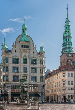 Foto de Copenhague, Dinamarca - 15 de septiembre de 2010: Estatua de la fuente de cigüeña en Amagertorv, en el centro de la ciudad, en su entorno urbano contra el cielo azul. Arquitectura moderna y torre Nikilaj Kunsthallen - Imagen libre de derechos