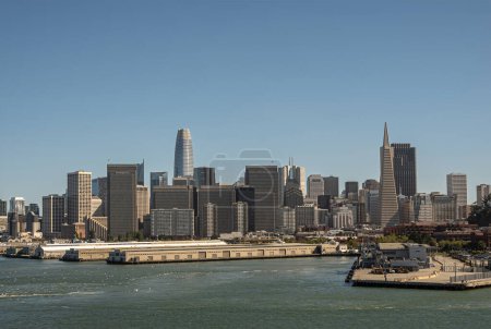 Photo for San Francisco, CA, USA - July 13, 2023: Pamorama, financial district with its skyscrapers behind several port docks and warehouses under blue sky. Salesforce and TransAmerica stand out - Royalty Free Image