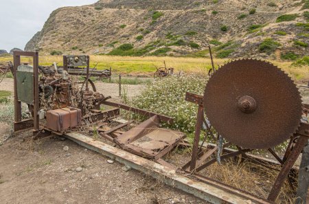 Photo for Santa Cruz Island, CA, USA - September 14, 2023: Old, rusted, broken machine remnants at Scorpion Ranch. Motor and huge mechanical saw. Smugglers trail on hill side at backdrop - Royalty Free Image