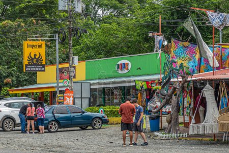 Téléchargez les photos : Costa Rica, Luganillas - 22 juillet 2023 : Les commerces de détail Tarcoles River et Crocodile bridge. Touristes devant plusieurs magasins exposant des marchandises. Panneaux de promotion des marques. Feuillage vert - en image libre de droit