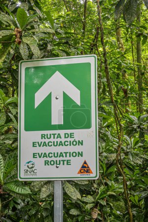 Photo for Costa Rica, Parque Nacional Carara - July 22, 2023: Green-white Evacuation sign showing which way to run in middle of rain forest in case of disaster. - Royalty Free Image