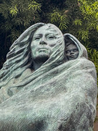 Téléchargez les photos : Santa Barbara, CA, États-Unis - 19 janvier 2024 : Statue en bronze vert de Juana Maria and Child. Feuillage vert à l'arrière. Femme seule de l'île San Nicolas, alias Sacagawea - en image libre de droit