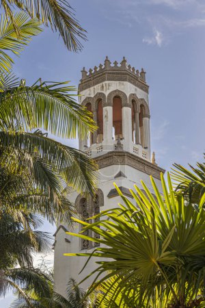 Foto de Santa Barbara, CA, Estados Unidos - 30 de noviembre de 2023: Torre de Nuestra Señora de los Dolores iglesia contra el cielo azul, asomándose por el follaje de la palmera verde - Imagen libre de derechos