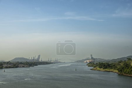 Panama Canal, Panama - July 24, 2023: View from Miraflores locks to Pacific ocean with Bridge of the Americas on horizon together with container handling cranes on docks. wide landscape