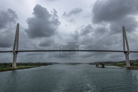 Panama Canal, Panama - July 24, 2023: Atlantic suspension bridge panorama just out of Canal under gray cloudscape. Colored pipeline floaters in water, Cutter Suction Dredger Quibian 1