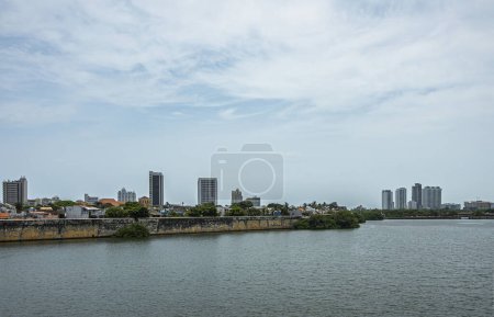 Cartagena, Kolumbien - 25. Juli 2023: Blick über die Altstadt von der römischen Brücke Puente aus. Historische befestigte Ufermauern unter hellblauer Wolkenlandschaft. Wenige hohe Gebäude